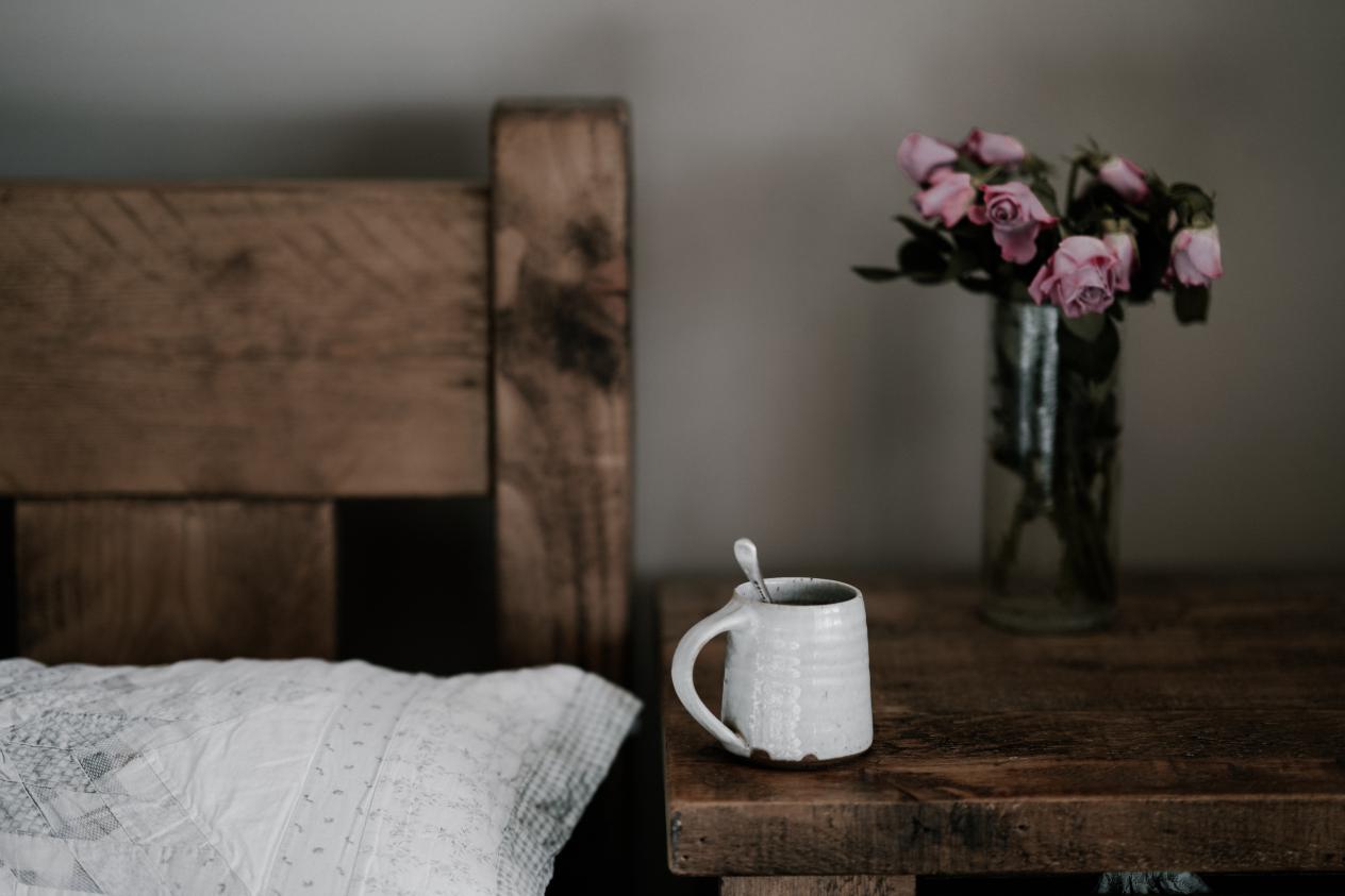 a white pillow and a bunch of flower on the night table